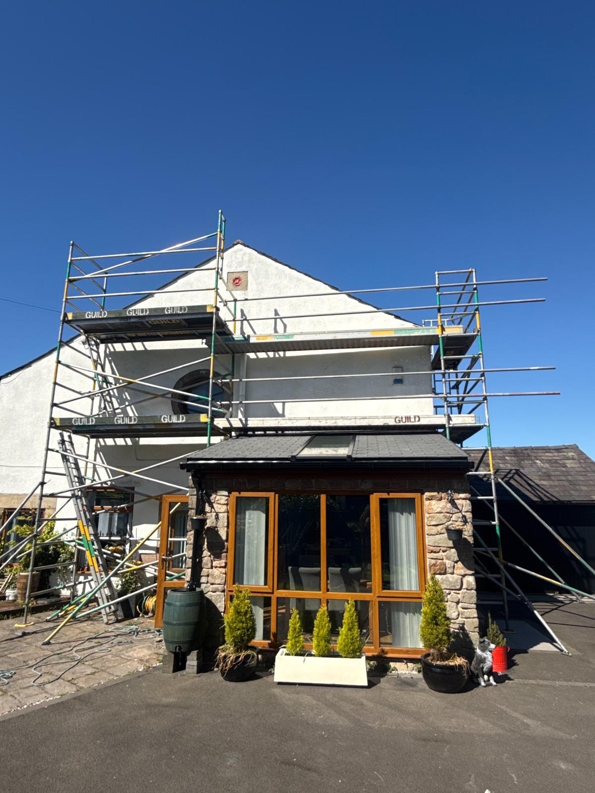White-painted terraced house with Guild Scaffolding wrap, well-kept front garden